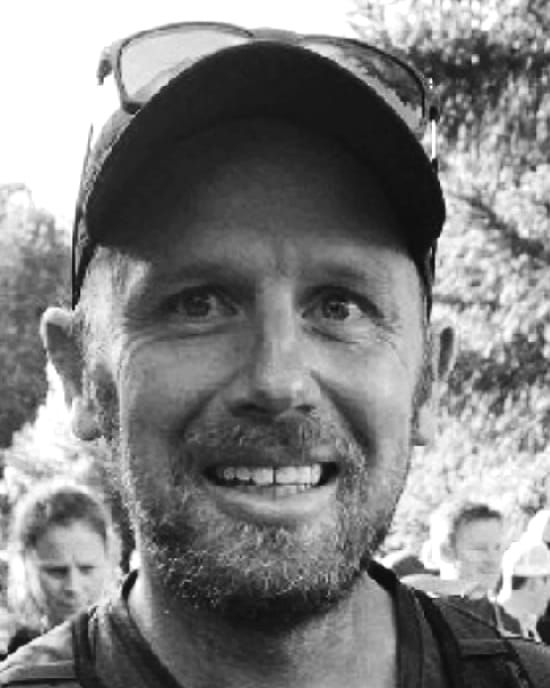 Duncan Crawford, smiling, in a cap and sunglasses outdoors